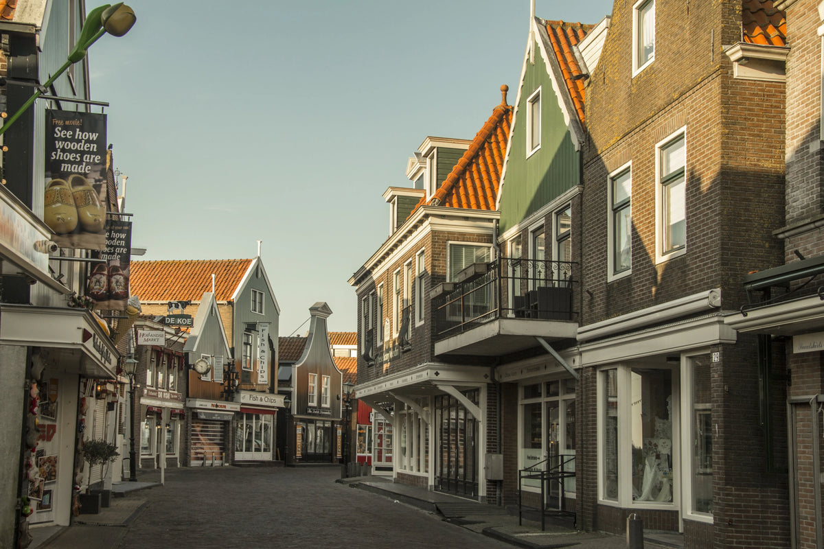 Charming European street scene with traditional architecture, shops, and a clear blue sky, perfect for travel-themed projects.