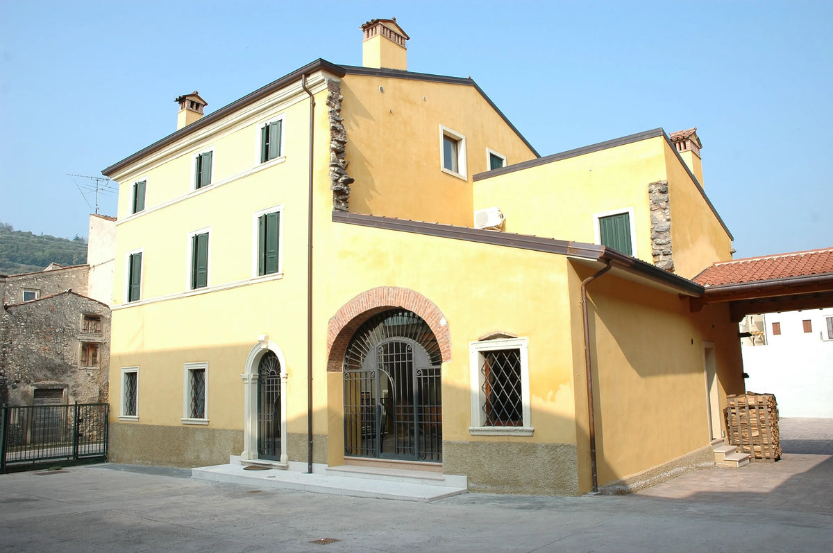 Charming yellow building with green shutters, featuring arched entrances and a stone facade, ideal for file storage.